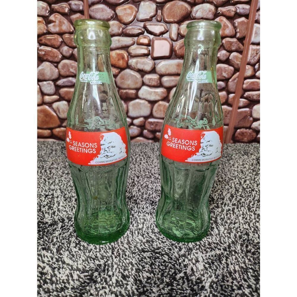2 Vintage Christmas 8 oz Green Glass Coke SEASONS GREETINGS Commemorative Bottle